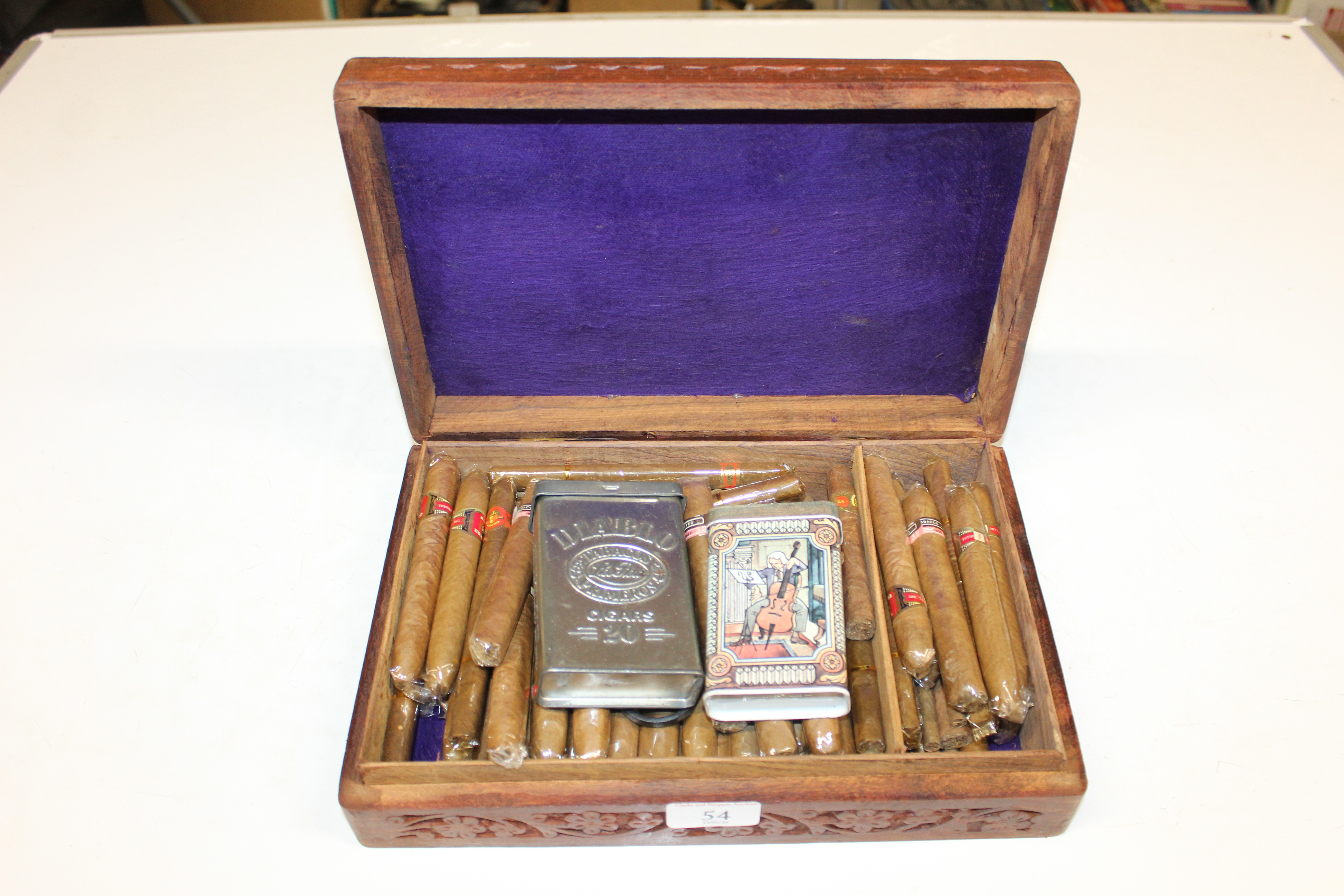A carved hardwood box and contents of various ciga