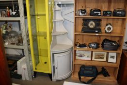 A grey painted corner unit raised on cupboard base