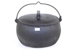 A large oval 4 gallon cast iron cooking cauldron with lid and metal swing handle