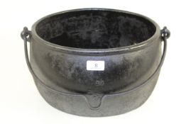 An oval 2 gallon cast iron cooking cauldron with swing handle