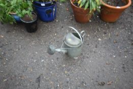 A galvanised one gallon watering can with rose