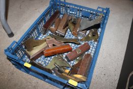A plastic crate containing various brass fire place ornaments in the form of shoes