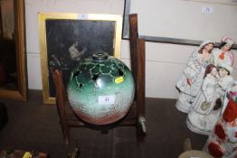 A Lynne Taylor green glazed pottery sphere on wooden stand