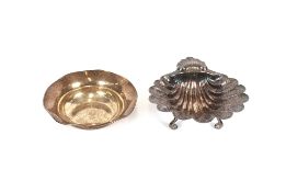 A silver shell shaped dish, having foliate engraved decoration, raised on three scrolled feet,