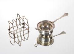 A silver tea strainer and bowl, London 1928/29; and a small silver four division toast rack,