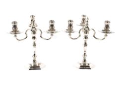 A pair of cast silver candelabra, having detachable three light tops on baluster columns and