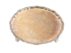 A silver salver, with gadrooned pie crust border raised on four stylised feet, Sheffield 1929,