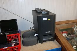 A Bose Acoustimaus Module speaker and two others together with a remote control