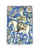 An antique Isnek tile, depicting figure on horseback with bird of prey, floral surround on a blue