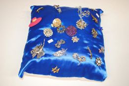 A cushion of various costume brooches