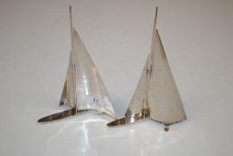 A pair of chromed model yachts, both marked to the