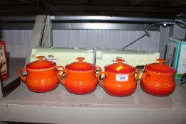 Four Le Creuset orange soup pot and covers and ori