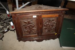 A carved oak corner cupboard