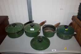 Four green Le Creuset saucepans, three having lids