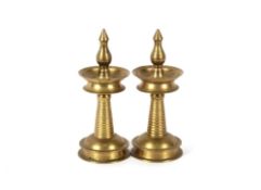 A pair of 20th Century Indian brass Kerela oil lamps with projecting finials, dished sconces, ring