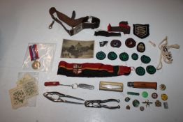 A box containing a Girl Guide belt, various badges, a pair of nut crackers, pen knives, WWII medal