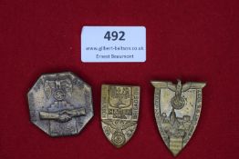 Three Third Reich period event badges. Including: a tall bronze-coloured badge with eagle and