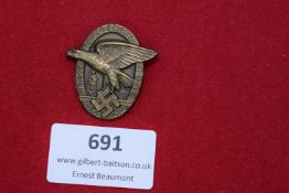 A scarce bronze badge depicting a flying eagle clutching a swastika, with the legend 