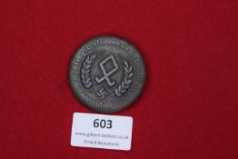 Circular pressed zinc badge with swastika and agricultural rune between corn ears, inscribed