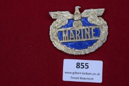 Pressed paper/fibreboard badge with gilt eagle and wreath, blue centre with “Marine” inscription,