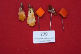 Five small pieces of amber and bakelite, fashioned as pin brooches. Includes carved amber pendants