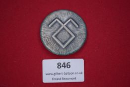 German tinnie badge with stylised rune design.