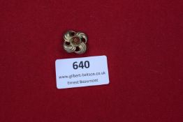 Decorative Floral Badge A small, ornate gilt badge in the form of a four-petaled stylised flower