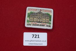 A colourful embroidered and framed pin badge, showing Schloss Jägerhof with surrounding trees and