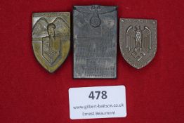 Three badges: a shield-shaped bronze-finish tinnie for the Reichskolonialtagung Bremen 1938; a