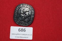 Darkened zinc badge with large swastika over crossed swords, inscribed 