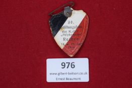 Paper and card badge in shield form, coloured in black, white and red, commemorating the 30th