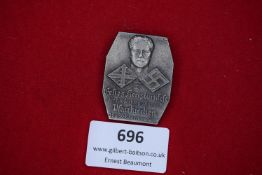 A commemorative badge showing a portrait head with swastika and emblem, inscribed “Festes