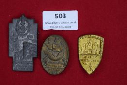 Three badges: a tall rectangular grey metal tinnie for Frontkämpfer Tag, Essen, 1936, with helmet