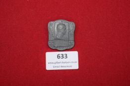 A scarce grey metal commemorative badge featuring the profile of a man in uniform, flanked by