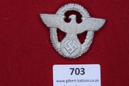 An aluminium die-stamped police cap badge in the form of the eagle and wreath, with central