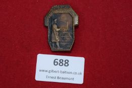 A bronze pressed badge depicting a German soldier on guard with rifle, overlooking a railway bridge,