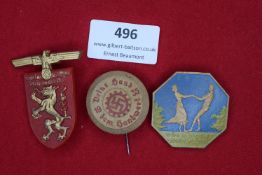 Three badges: a red plastic shield-shaped badge with gilt eagle and lion for Gautag Steiermark 1939;