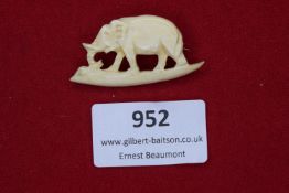 A small hand-carved brooch in the form of an elephant with raised trunk, made from bone or similar