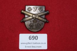 A bronze badge in the form of a shield with crossed cannons, swastikas and the number 7, dated