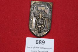 A shield-shaped bronze badge, showing Freiburg Cathedral above a sword and wreath with swastika,