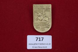 A pressed metal shield-shaped tinnie commemorating the 650th anniversary of the Battle of