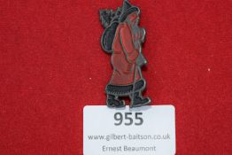 A novelty pressed metal badge depicting Father Christmas in red enamel, carrying a sack and