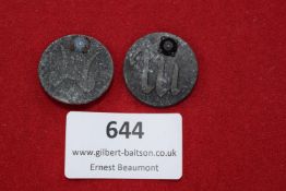 Two circular badges, each inset with a coloured stone at the top, one decorated with a stylised ‘