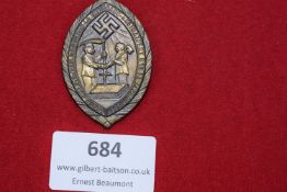 Oval pressed brass badge with swastika and figures of farmer and worker shaking hands, inscribed 