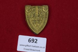 A gilt shield-shaped tinnie commemorating the 1st West German War Victims’ Day, held in Dortmund and