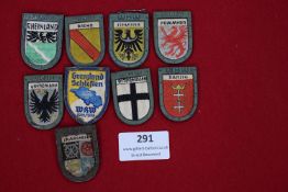 A lot of 8 WHW (Winterhilfswerk) metal-framed cloth shields, each representing different German regi