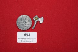 Two-piece set comprising a small round shield badge and axe-form badge, cast in grey metal with