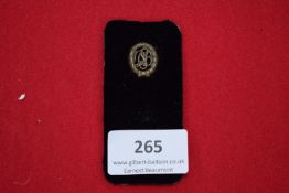 Female RAD Brooch, a small bronze badge with stylised monogram within a laurel wreath, mounted on