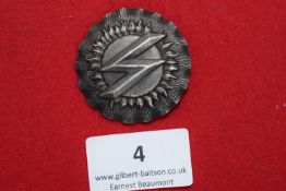 Sonnenrad Badge, a circular dark bronze badge with radiating sun motif surrounding double “S”