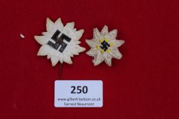 Pair of Edelweiss Badges, one painted metal with black swastika centre, the other embroidered